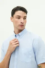 Camisa de manga corta color beige claro, confeccionada en lino y algodón, con fit regular y logo bordado en el pecho.