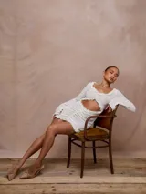 Minivestido blanco de mangas largas con volados, transparencias y abertura en el abdomen.