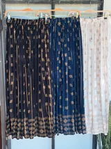 Falda larga negra con estampado dorado, cintura elástica y corte amplio.