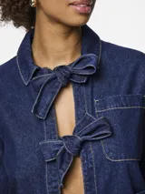 Camisa de denim azul con cuello clásico, cierre frontal con lazos y bolsillos de parche.