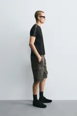 Bermuda cargo de algodón color marrón oscuro, tiro medio, corte regular, con bolsillos laterales de parche con solapa y bolsillos traseros de vivo.