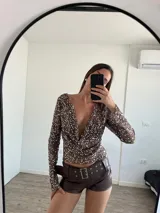 Top de fiesta color blanco, con escote drapeado y lentejuelas.