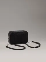 Cartera bandolera Calvin Klein negra con diseño acolchado de líneas verticales, correa de cadena plateada, cierre superior con cremallera y logo metálico frontal.