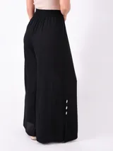 Pantalón palazzo negro con cintura elástica y cordón ajustable. Presenta aberturas laterales con botones blancos.
