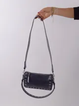 Bandolera color rojo de cuero con tachas plateadas. Tiene dos asas desmontables, una corta con tachas para llevarla en la mano o al hombro y una larga para llevarla al hombro o cruzada. Tiene bolsillo interior con cierre y forro.