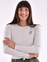 Remera blanca de manga larga con cuello redondo y estampado pequeño con la frase 'Busy ignoring someone' en el pecho.