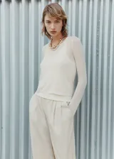 Jersey de punto fino color crema, con cuello redondo, diseño recto y mangas largas. Incluye una musculosa al tono.