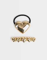 Set de accesorios para el pelo que incluye una hebilla francesa dorada con cinco corazones y una gomita elástica negra con aplique de corazón dorado.