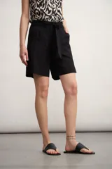 Short de vestir color beige claro, tiro alto, con pliegues frontales y lazo para ajustar la cintura.