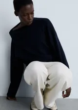 Sweater de punto azul marino con cuello alto asimétrico envolvente y manga larga.