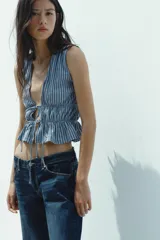 Top amarillo con estampado de cuadros vichy blancos, escote en pico, sin mangas, con detalle de elásticos en la cintura y cierre frontal con lazadas.