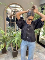 Camisa negra con mangas abullonadas y botones frontales.