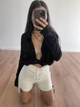 Short blanco de bengalina elastizada con cordones cruzados en la parte delantera y flecos en los laterales.