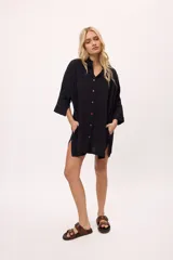 Vestido camisero a rayas verticales de colores pastel, con cuello camisero, cierre frontal con botones y mangas largas.