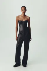 Top tipo corsé negro de cuero sintético, con escote corazón y hombros descubiertos. Detalle de costuras marcadas y cierre trasero con cremallera.