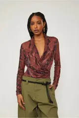 Body de poliéster y elastano con estampado de piel de serpiente en tonos marrones y negros. Tiene mangas largas, escote en V cruzado y calce ajustado al cuerpo.