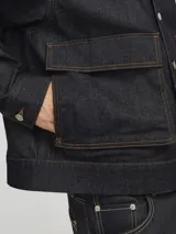 Campera de denim azul oscuro con cuello clásico marrón, cierre frontal con botones metálicos, bolsillos delanteros con solapa y puños con botones. Confeccionada en tejido denim resistente con estructura de sarga.