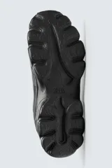 Zapatillas deportivas color crema con cordones, suela gruesa con diseño irregular y detalles en gris.