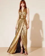 Vestido largo dorado confeccionado en malla metalizada, con escote halter en V con lazos al cuello, fajín fruncido en la cintura y abertura frontal.