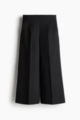 Pantalón palazzo negro de tiro alto con elástico oculto en la cintura, cierre lateral oculto y pinzas que realzan la figura. Modelo de corte holgado con bolsillos al bies, bolsillos decorativos atrás y piernas tres cuartos con raya adelante y atrás.