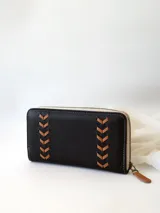 Billetera negra de cuero con cierre metálico, diseño con pespuntes en forma de espiga y logo de la marca en etiqueta de cuero. Incluye monedero interno y espacio para billetes extendidos.