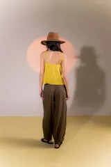 Pantalón de lino color marrón, con corte tipo barrel, tiro medio, pretina ancha con doble abotonadura, bolsillos laterales y pinzas en el frente. Ruedo con presilla permitiendo usarlo recto o fruncido al tobillo.