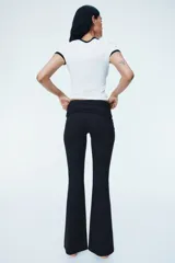 Pantalón de yoga negro de microfibra suave, con cintura alta de doble capa, costuras laterales fruncidas y piernas acampanadas.