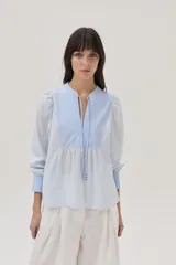 Blusa celeste a rayas verticales blancas, con cuello mao con lazos, mangas abullonadas y corte imperio.