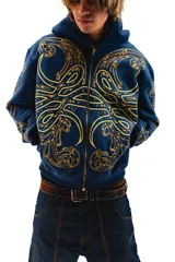 Hoodie azul con cierre y bolsillos laterales, con estampado dorado de hojas de acanto en el frente y las mangas.