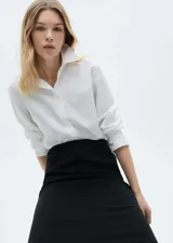 Camisa blanca de popelina de algodón y lyocell, corte recto, manga larga con puños abotonados y cuello camisero.