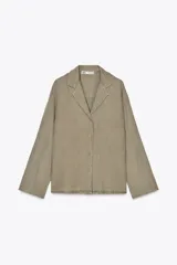 Camisa color verde oliva confeccionada en lino 100%. Tiene cuello solapa, escote pico, manga larga con botones y bajo recto. Cierre frontal con botones.