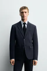 Blazer slim fit color verde oliva, confeccionada en tejido con viscosa. Tiene cuello con solapas de muesca, manga larga con puños abotonados, bolsillo de vivo en el pecho, bolsillos de solapa en la cadera, bolsillo interior, aberturas en la espalda y cierre frontal con botones.