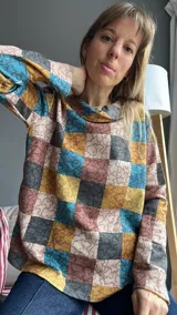 Sweater de punto con cuello alto y mangas largas, con diseño de bloques de colores en tonos marrón, beige, azul y amarillo.
