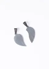 Set de dos dijes plateados de acero quirúrgico con forma de corazón partido para compartir en pareja.