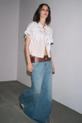 Top de tejido satinado color blanco, con cuello redondo, manga corta y detalle de puntilla a tono. Cierre frontal con lazadas.