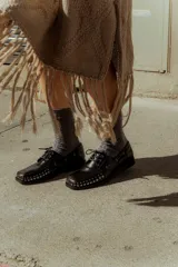 Mocasines de cuero negro con tachas plateadas en la puntera y laterales.