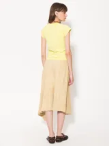 Falda midi color beige de gamuza arrugada, corte irregular y diseño tipo portafolio.