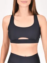 Top deportivo negro con escote redondo y abertura en el centro del pecho.