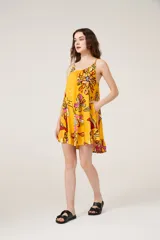 Vestido corto amarillo con estampado de flores, breteles finos y cuello redondo.