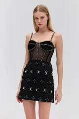 Vestido corto negro sin mangas confeccionado en terciopelo, con corsé de tul con ballenas y tirantes finos ajustables de terciopelo. Presenta broche y bordado de piedras, falda de terciopelo de encaje y cierre de cremallera invisible.
