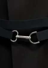 Abrigo largo negro con cuello de solapa, manga larga con puños abotonados, cinturón desmontable con hebilla metálica, bolsillos laterales y abertura en la parte posterior.