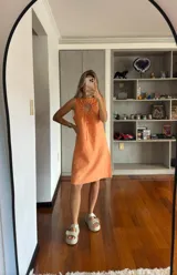 Vestido corto color naranja, sin mangas, con escote redondo y detalle de abertura con lazos en el pecho.