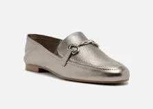 Mocasín plateado de cuero con detalle de hebilla metálica.