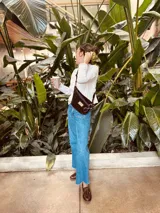 Riñonera de gamuza color chocolate con cierre azul marino y correa ajustable.