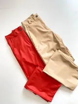 Pantalón de ecocuero rojo y beige, tiro alto y corte recto.