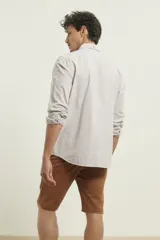 Camisa de manga larga a rayas verticales finas color blanco y gris, con cuello abotonado y bolsillo en el pecho.