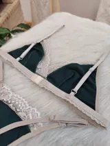 Conjunto de lencería de algodón color verde inglés con detalles de encaje nude, compuesto por un bralette de corte triangular con breteles regulables y una tanga con laterales ajustables.