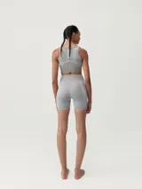 Top deportivo color gris con líneas decorativas blancas, de sujeción alta y copas extraíbles.