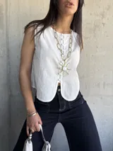 Chaleco blanco con botones al frente y corte irregular en el ruedo.