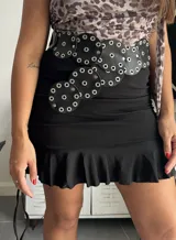 Minifalda negra ajustada al cuerpo con volado inferior y laterales ajustables con cordones.